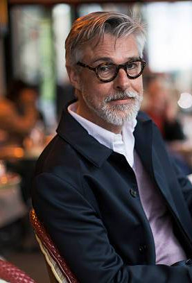 Man sitting at a cafe table using a smartphone with a blurred background